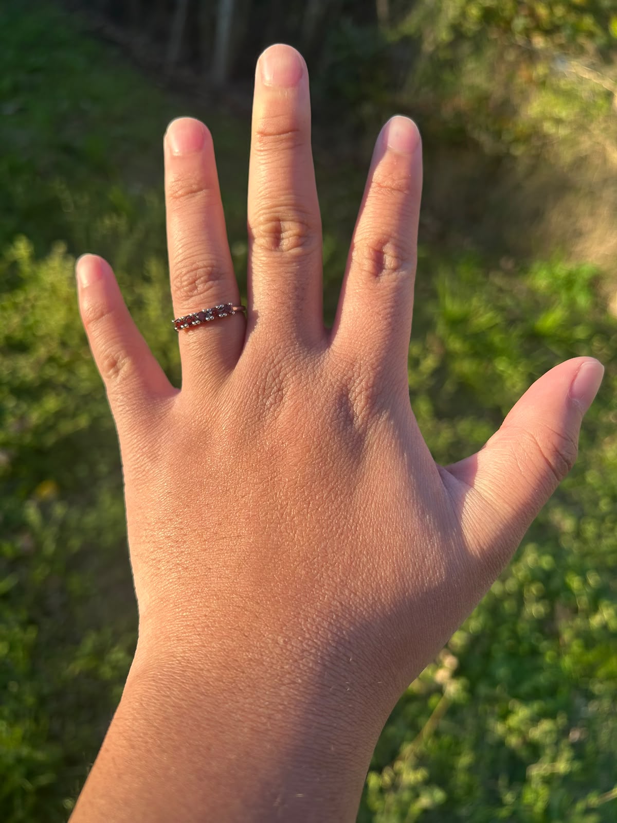 Anillo Cinco Brasas KLORE con cinco piedras de granate puesto en la mano